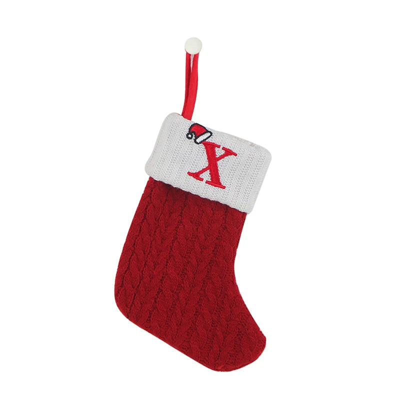 A red knitted sock with a white cuff featuring a red letter X and a hanging loop for tree decoration.