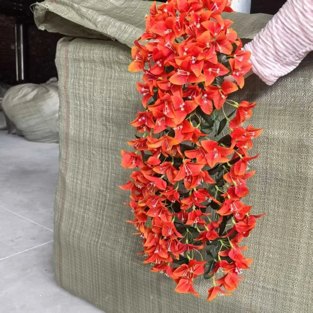 A vibrant orange faux bougainvillea vine with small flowers is displayed against a textured green fabric.