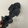 A black vintage wrought iron wall-mounted candle holder with an ornate, scrolled design.