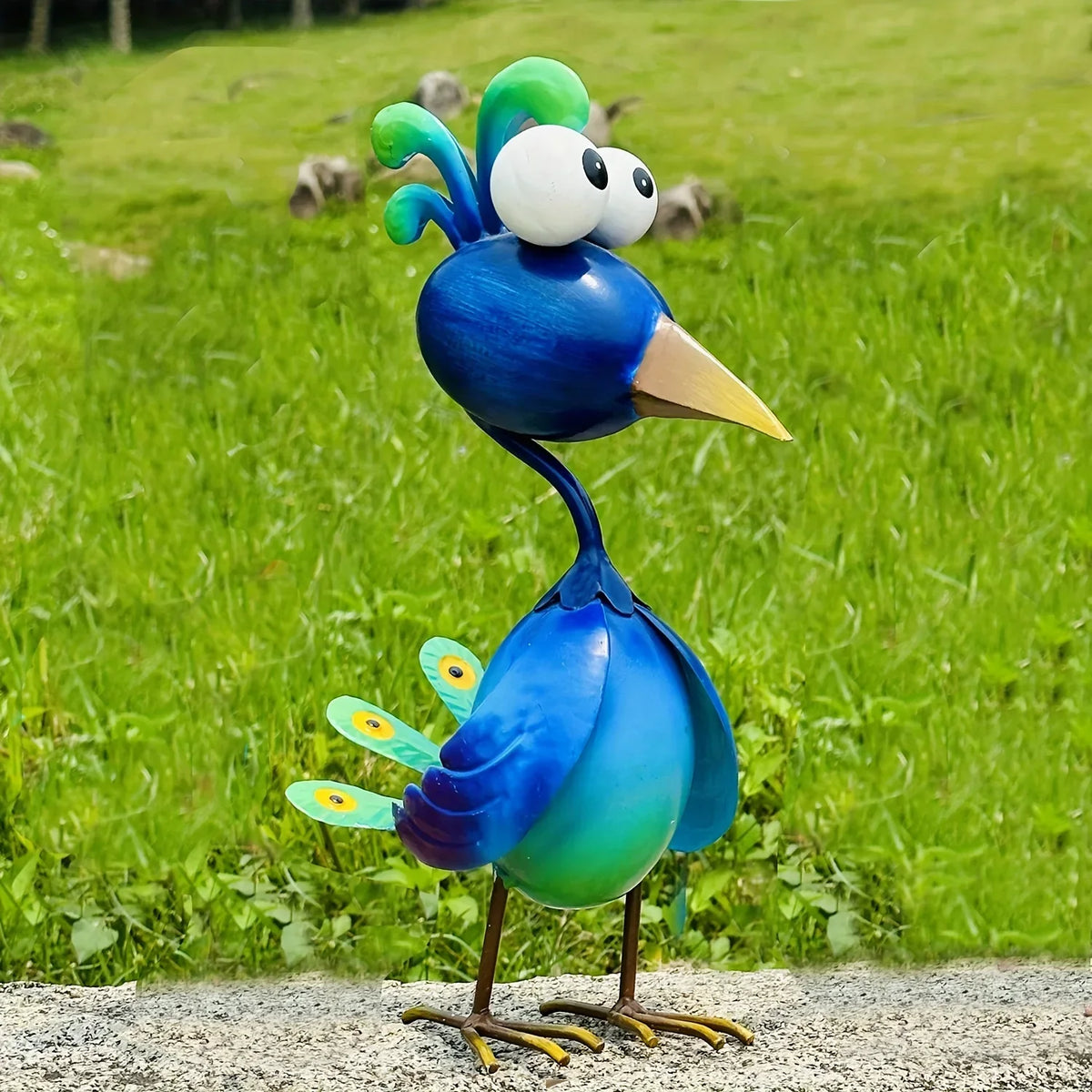 A vibrant blue metal peacock garden sculpture with bright green crests standing on a gray surface.