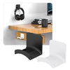 A black universal wall-mounted headphone holder and hanger displayed next to a wooden desk.