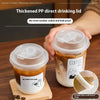 A hand holds a clear disposable coffee cup with a lid, showing a layered drink, next to a wooden board and a strip.