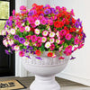 A vibrant bouquet of artificial silk cloth flowers in shades of pink, red, and purple displayed in a white urn.