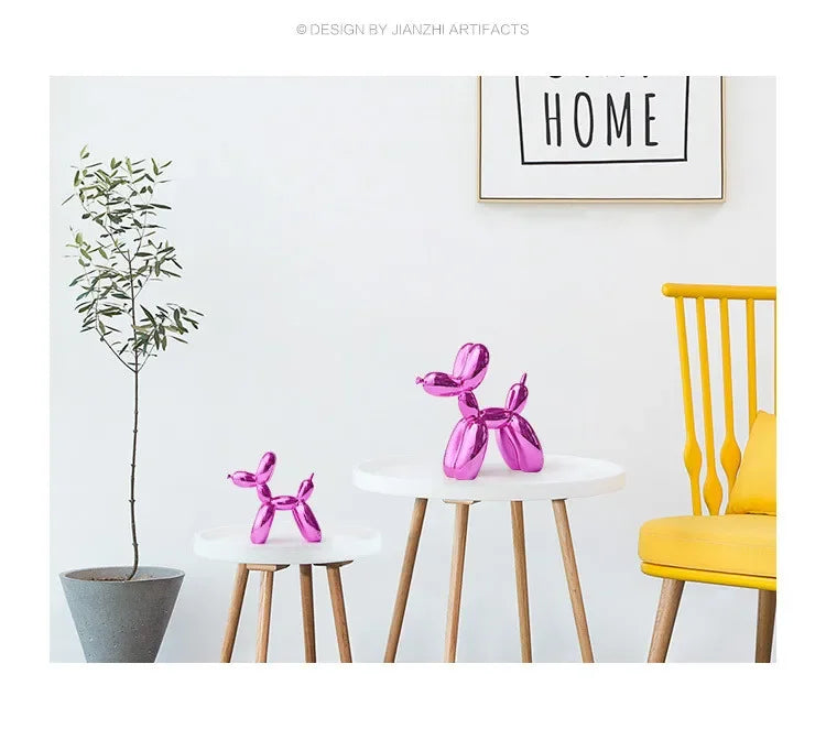 Pink resin balloon dog sculpture on a white table against a white wall with a yellow chair and a potted plant.
