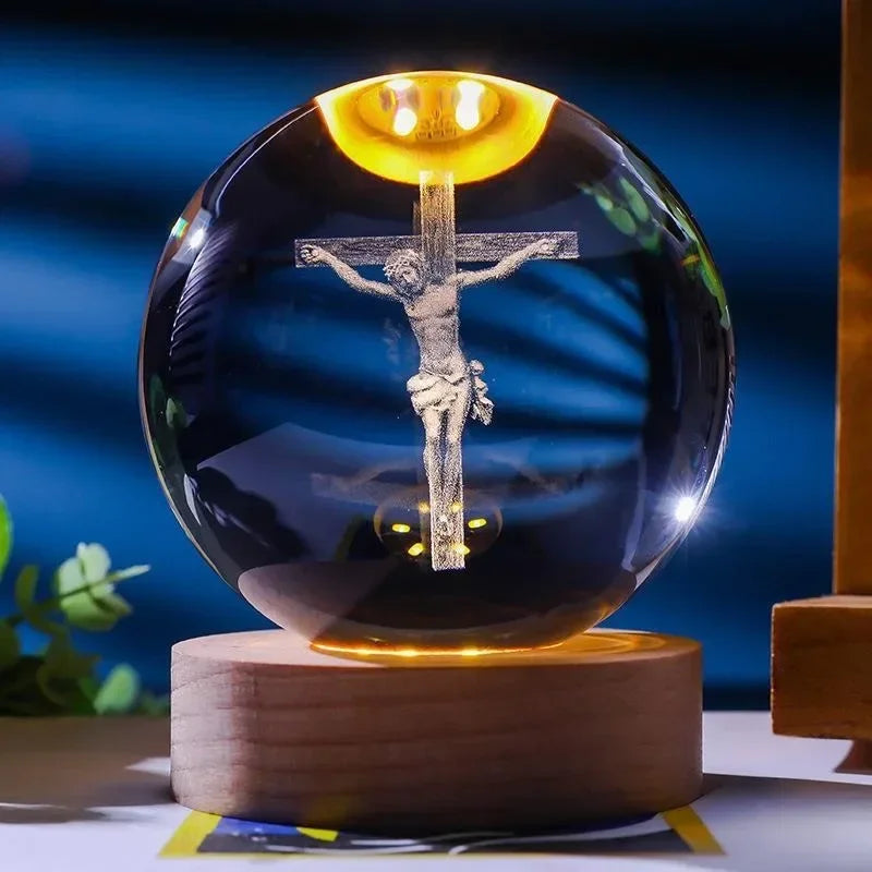 A dark glass crystal ball night light featuring a glowing crucifix silhouette against a dark background.
