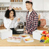 A man and a woman are preparing pastries in minimalist kraft sandwich boxes on a wooden table.