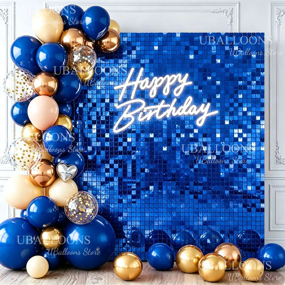 A collection of gold and blue balloons arranged around a bright blue sequin wall backdrop with Happy Birthday text.