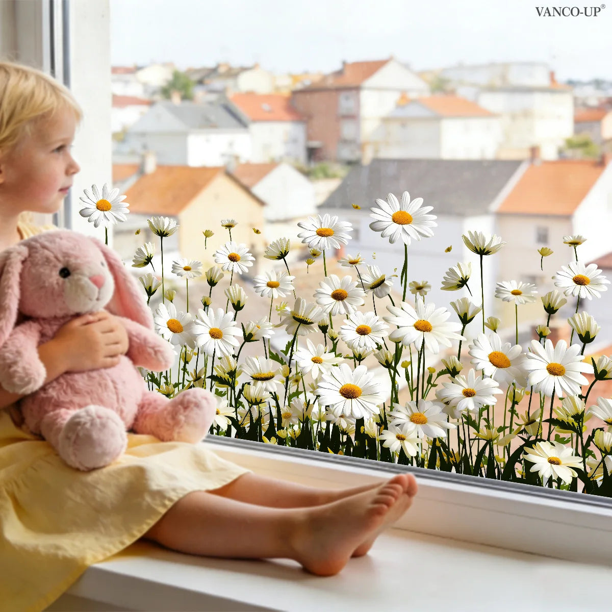 A young girl with blonde hair is sitting by a window looking at a field of white and yellow daisy flowers.