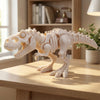 A white 3D printed dinosaur skeleton figurine featuring a T-Rex and Mosasaurus collectible displayed on a wooden table.