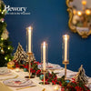 Three hurricane candle holders with gold and silver accents decorated with red berries on a white table.