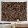 A leopard print tapestry wall hanging displayed above a wooden table and next to a light wood cabinet.