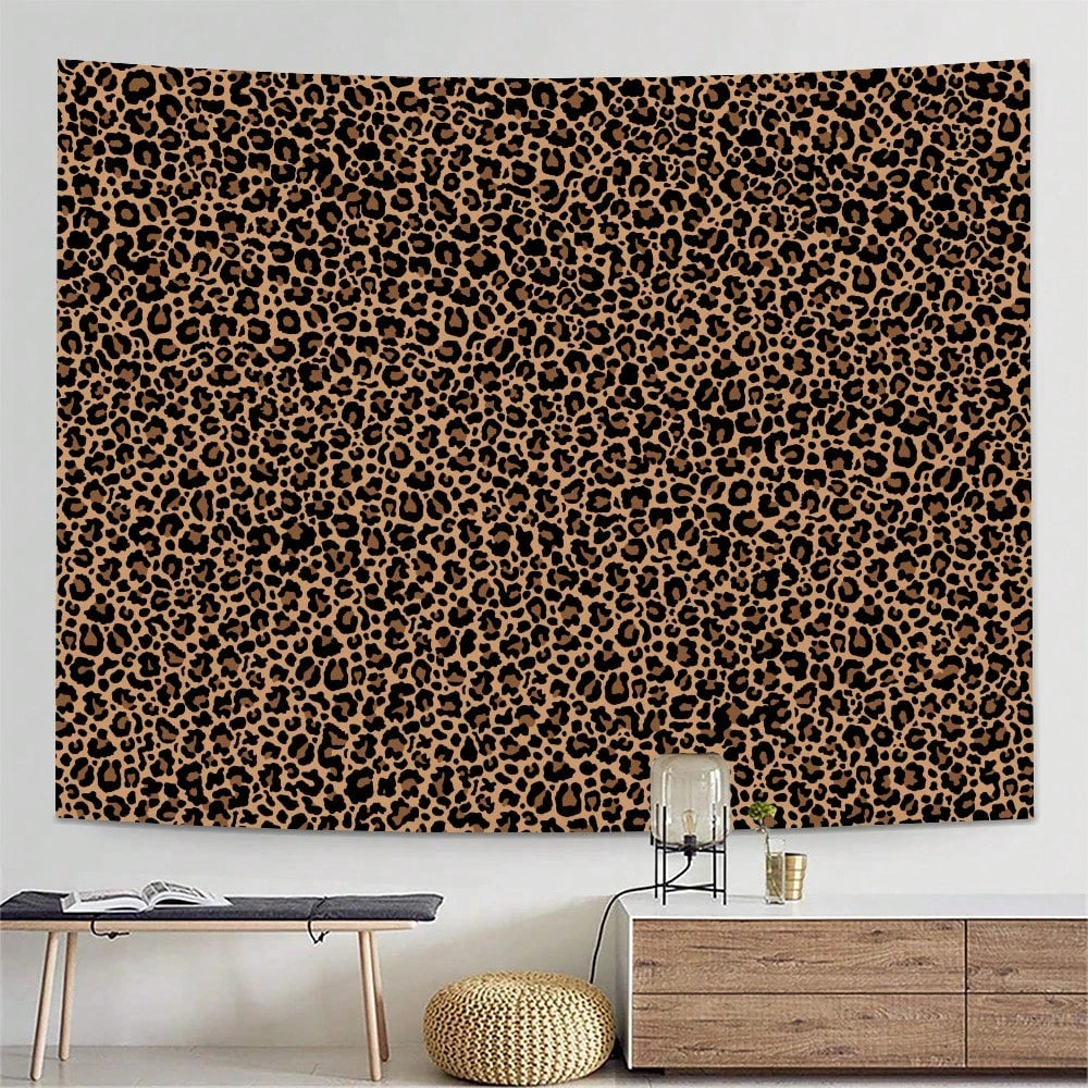 A leopard print tapestry wall hanging displayed above a wooden table and next to a light wood cabinet.