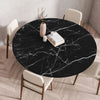 A round black marble print tablecloth is set on a wooden table with white chairs.