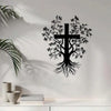 Black silhouette of a cross with leafy branches and roots on a white wall.