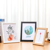 A rustic wooden photo frame with a plexiglass front displaying a botanical illustration of a cactus and leaves.