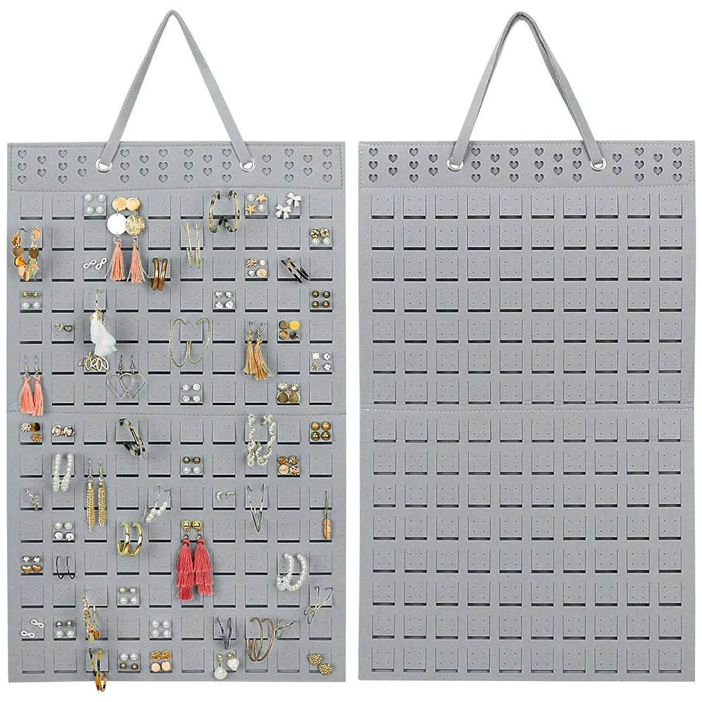 A gray wall mounted felt earring organizer display with numerous pairs of earrings neatly arranged in individual slots.