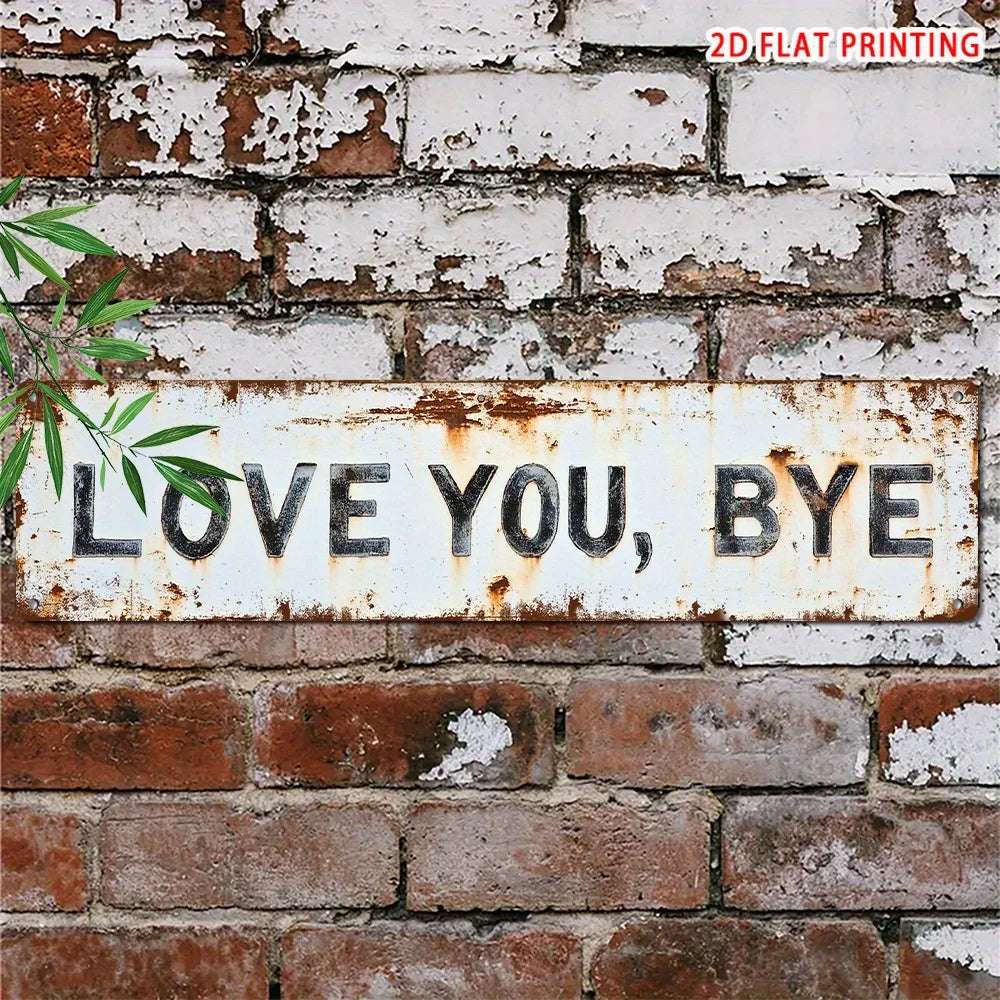 A distressed white metal sign with the text LOVE YOU BYE mounted on a brick wall.