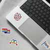 A laptop keyboard and touchpad display various LGBTQ pride and love themed stickers on a gray background.