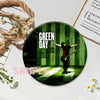 A button pin featuring a green striped background with a silhouette of a person playing a guitar.