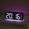 Reloj de alarma LED digital mostrando 20:16 en una superficie blanca con retroiluminación púrpura.