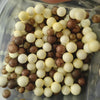 A collection of pastel foam beads in various shades including white, cream, and brown are displayed in a clear container.