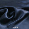 Dark blue satin fabric draped and folded to show its smooth texture