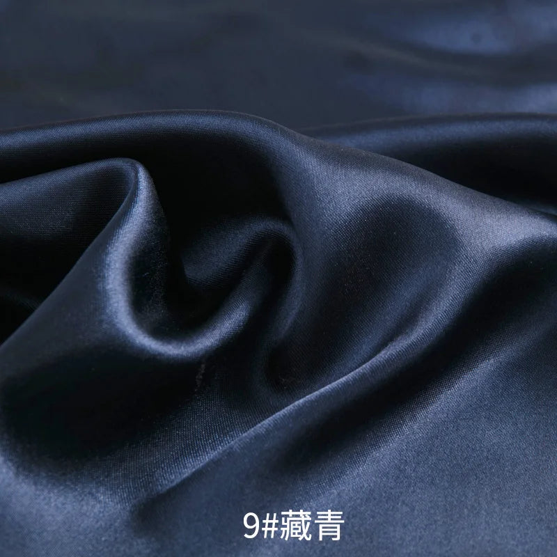 Dark blue satin fabric draped and folded to show its smooth texture