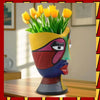 A colorful abstract resin decorative planter pot shaped like a face with yellow tulips blooming from the top.