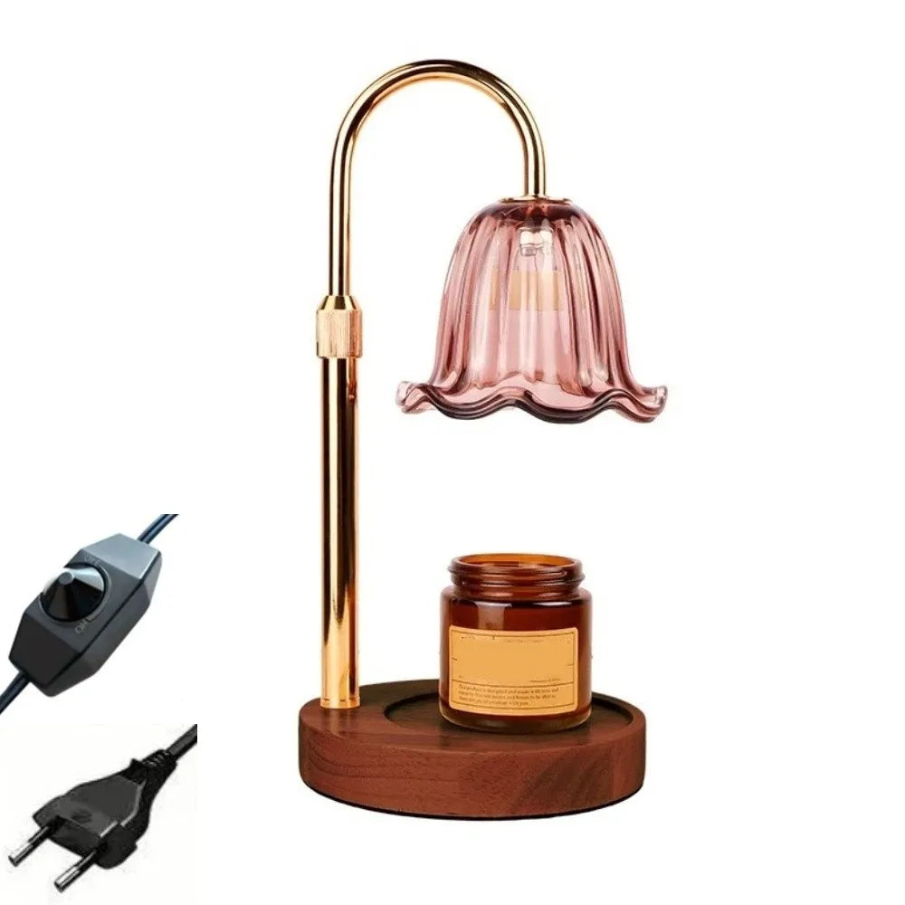 A gold-toned adjustable height aromatherapy candle warmer lamp with a pink glass shade and a wooden base.