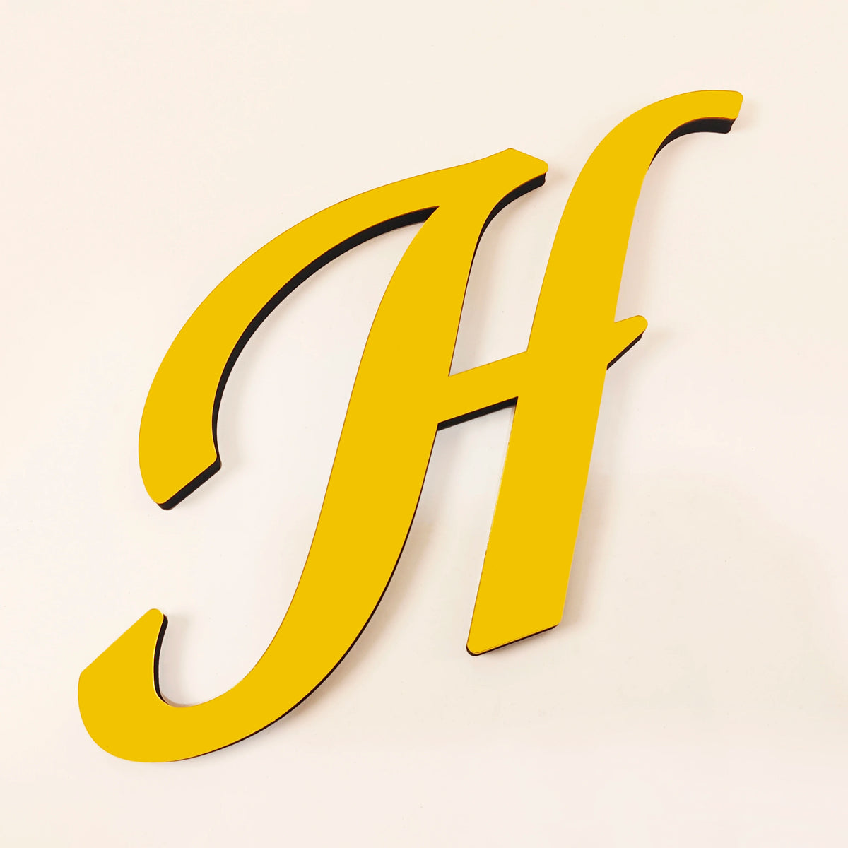 A large, gold 3D acrylic letter H is shown against a light background.