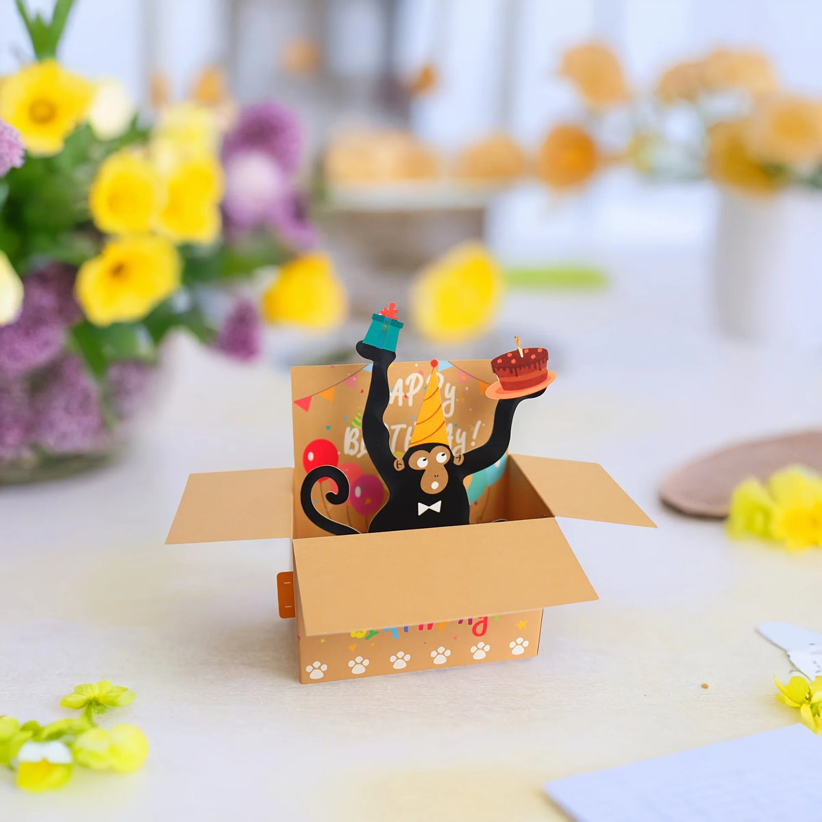 A humorous 3D pop-up birthday card featuring a monkey character holding heart balloons and confetti.
