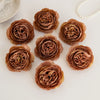 A collection of dried silk peony artificial flowers in shades of dusty rose and brown arranged on a white surface.