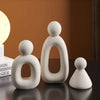 Three white resin figures representing a family in a modern style
