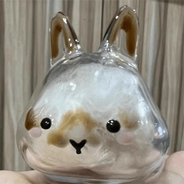 A clear glass figurine shaped like a rabbit with brown accents and black eyes.