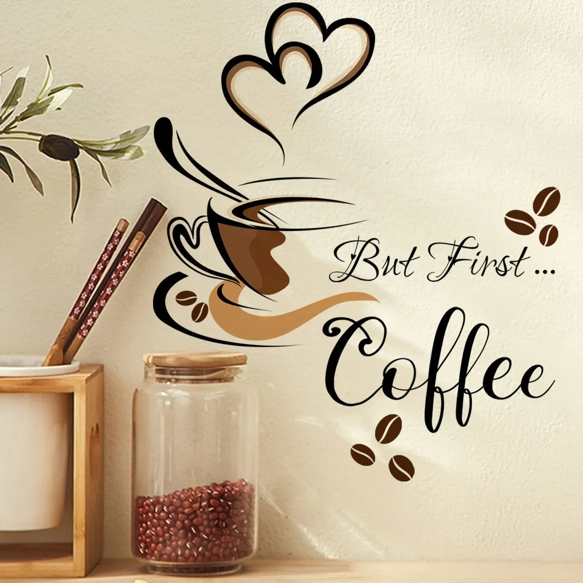 A wall sticker set featuring a coffee cup design and the text But First Coffee on a light-colored wall.