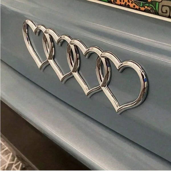 Silver heart-shaped badge sticker with a chain design mounted on a light blue cabinet door.