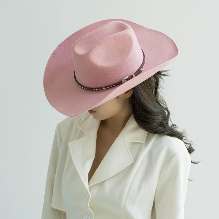 A woman wearing a pink felt cowboy hat with a studded leather band and a cream blazer.