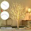 A decorative birch tree light with flexible and bendable branches illuminating a room.