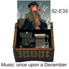 A hand-cranked wooden music box featuring an illustration of a woman and a bird, labeled 62-E39.