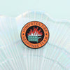 An enamel pin featuring a stylized orange and black design with flames and text for the Dumpster Fire Response Team.