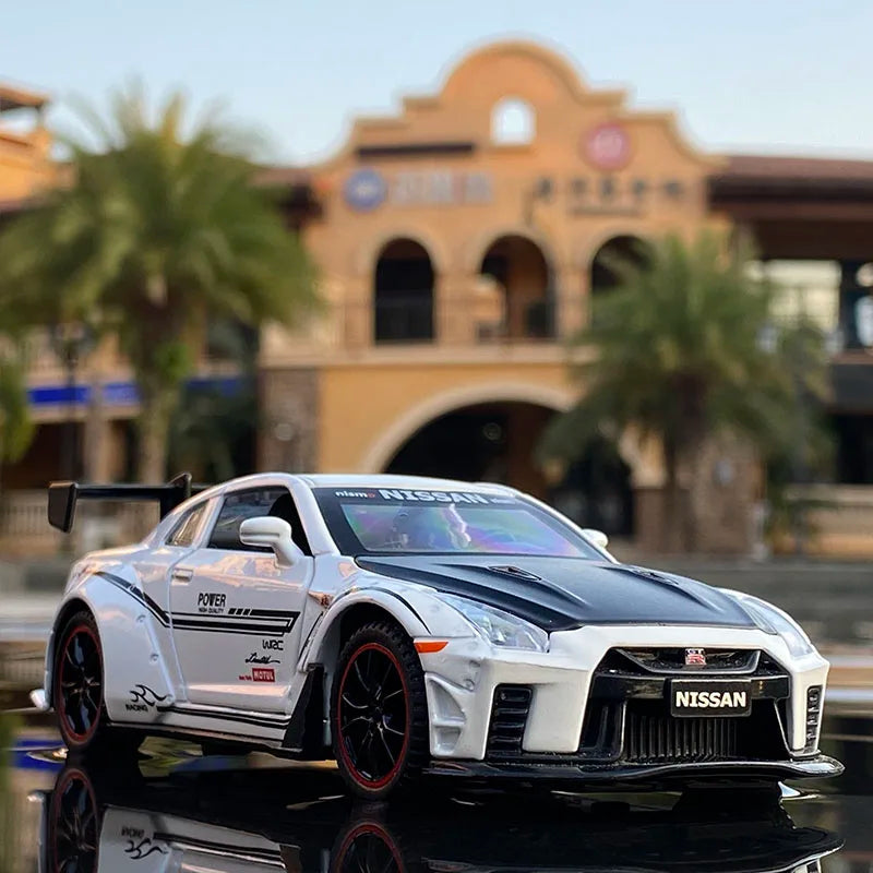 A white Nissan GT-R sports car model is displayed on a dark surface with a building in the background.