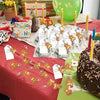 A display of cute bear keychain party favors with organza bags and thank you tags arranged on a red tablecloth.