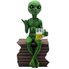 Green resin alien statue with a beer mug sitting on a wooden block.