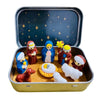A set of classic PVC Christmas nativity scene figurines, including Mary, Joseph, and baby Jesus, displayed in a storage tin.