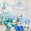 A collection of metallic chrome balloons in various sizes and shades of blue and white, decorated with a happy birthday banne