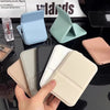 A hand holds a portable folding HD makeup mirror with various pastel colored cases and a stand.