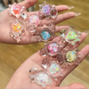 Una mano sostiene varias figuras pequeñas y translúcidas de tortugas marinas con acentos de brillo para decorar.