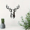 Black metal deer head wall sculpture against a white background with green foliage.