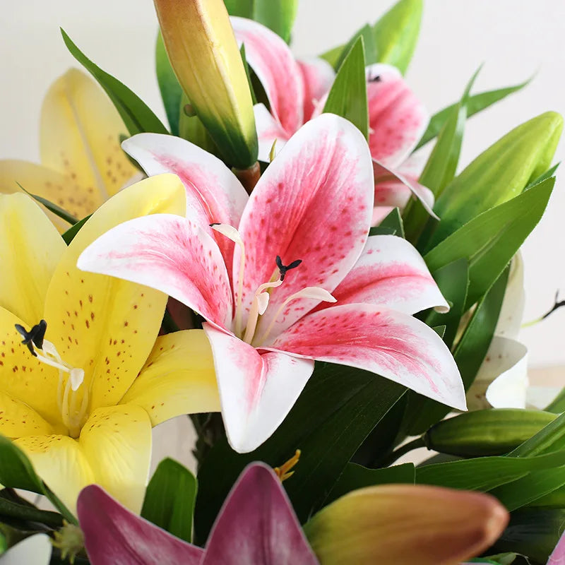 A bouquet of realistic silk lily flowers in shades of pink, white, and yellow with green stems.