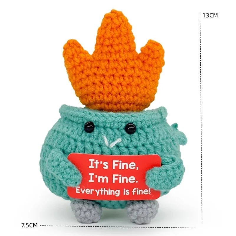 Handcrafted crochet animal doll in teal with a crown and a red card saying It's Fine I'm Fine Everything is fine